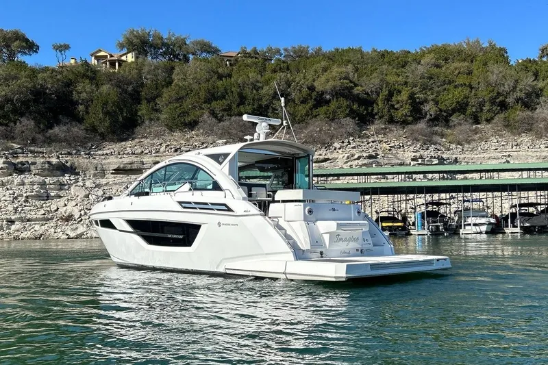 Slide: The Image of 2021 Cruisers Yachts 50 Cantius on serene water near rocky shoreline. - 19