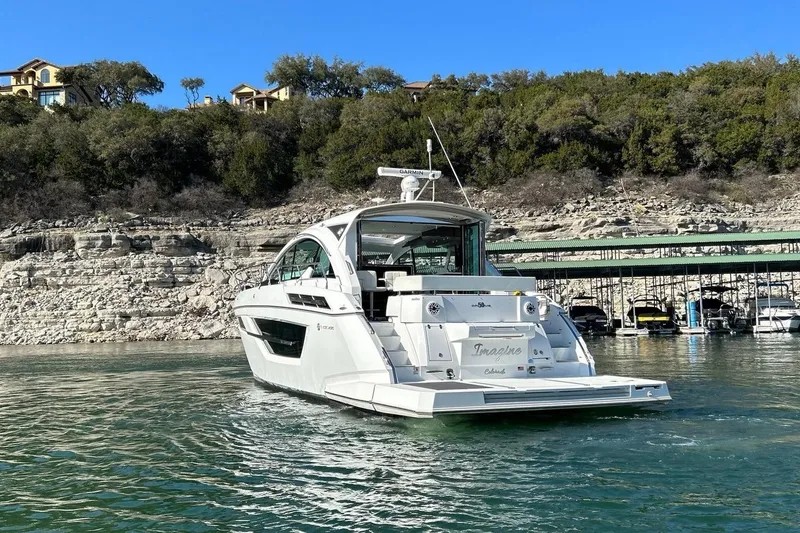 Slide: The Image of 2021 Cruisers Yachts 50 Cantius on scenic lake with rocky shoreline backdrop. - 20
