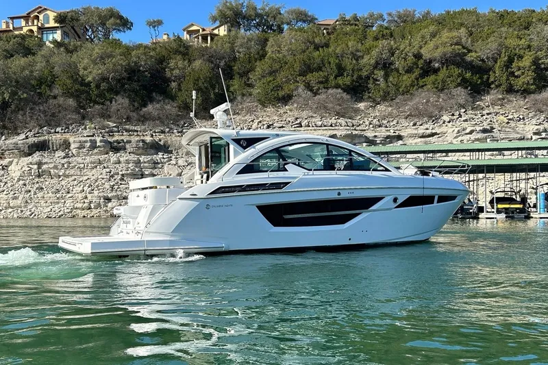 Slide: The Image of 2021 Cruisers Yachts 50 Cantius on serene lake with rocky shoreline backdrop. - 24