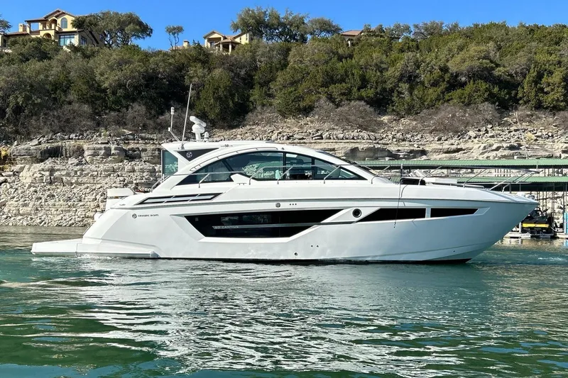 Slide: The Image of 2021 Cruisers Yachts 50 Cantius on serene water, with lush greenery in the background. - 25