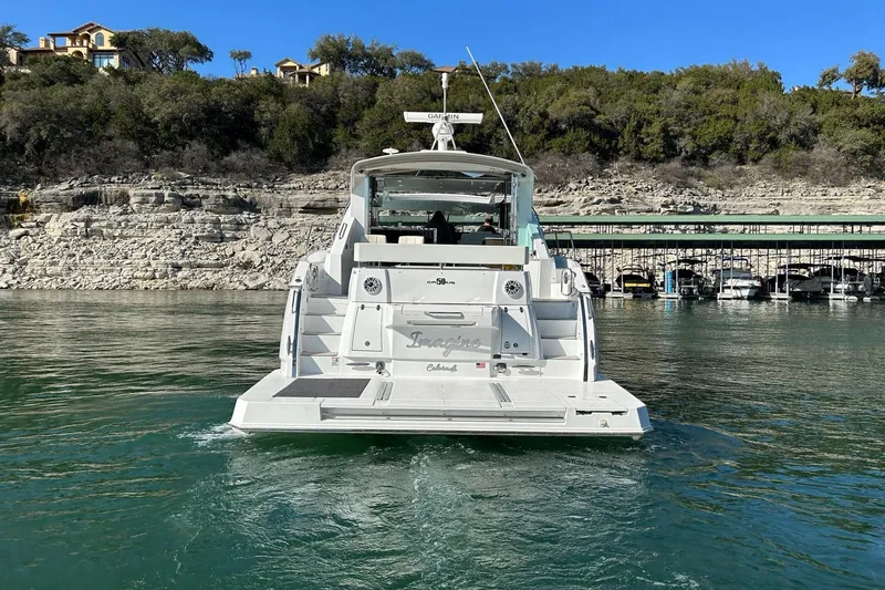Slide: The Image of 2021 Cruisers Yachts 50 Cantius on serene water with rocky shoreline backdrop. - 3