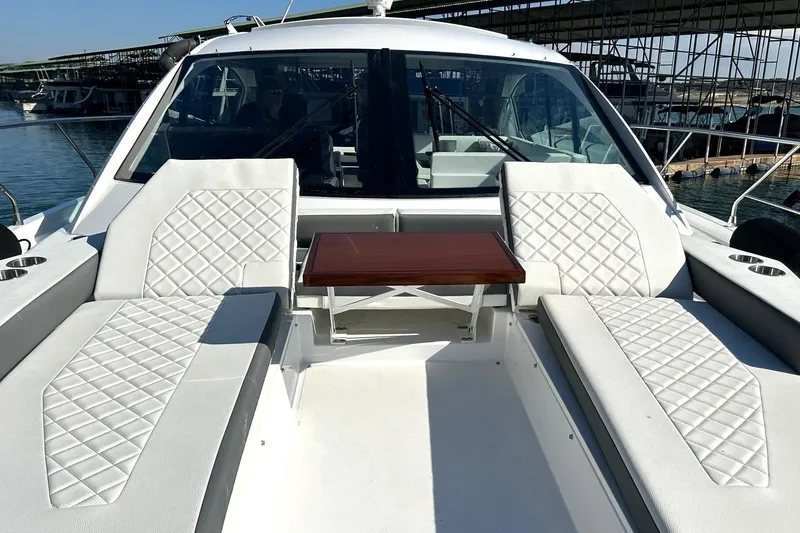 Slide: The Image of 2021 Cruisers Yachts 50 Cantius with luxurious white seating and wooden table on deck. - 43