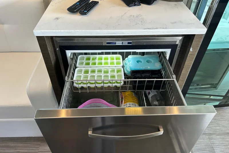 Slide: The Image of Drawer-style freezer in 2021 Cruisers Yachts 50 Cantius, stocked with ice trays and beverages. - 52