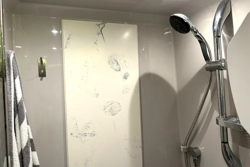 Slide: The Image of Shower area in 2021 Cruisers Yachts 50 Cantius with chrome fixtures and marble panel. - 91