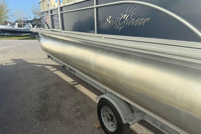 Slide: The Image of 2015 SunChaser 22 vs pontoon boat on trailer, side view in outdoor setting. - 5