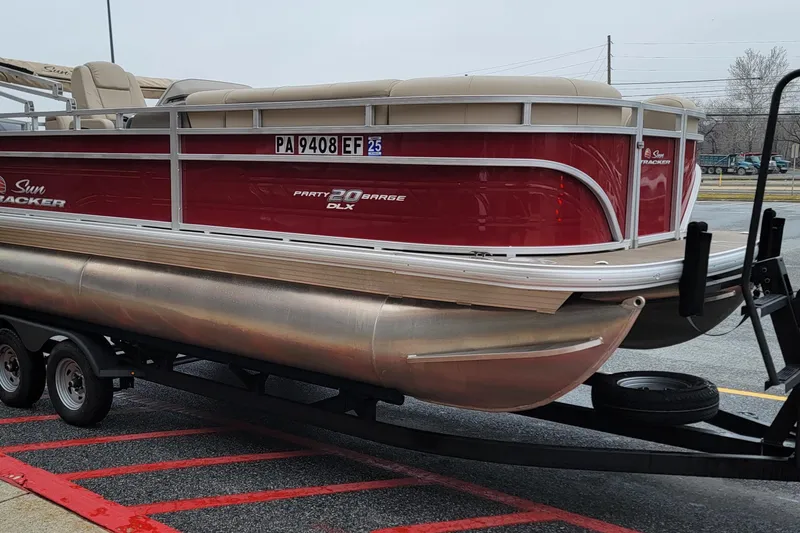 Slide: The Image of 2024 Sun Tracker Party Barge 20 DLX pontoon boat on trailer, red and beige design. - 10