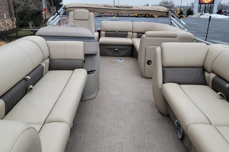 Slide: The Image of 2024 Sun Tracker Party Barge 20 DLX interior with beige seating and spacious layout. - 2