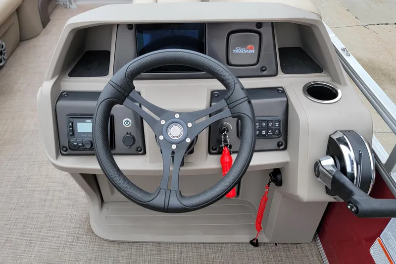 Slide: The Image of 2024 Sun Tracker Party Barge 20 DLX steering console with controls and cup holder. - 8