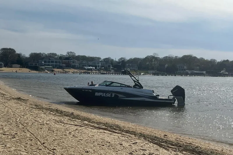 Slide: The Image of Boat named "Impulse 3" by Monterey, 2022, docked on a sandy beach with houses in the background. - 3