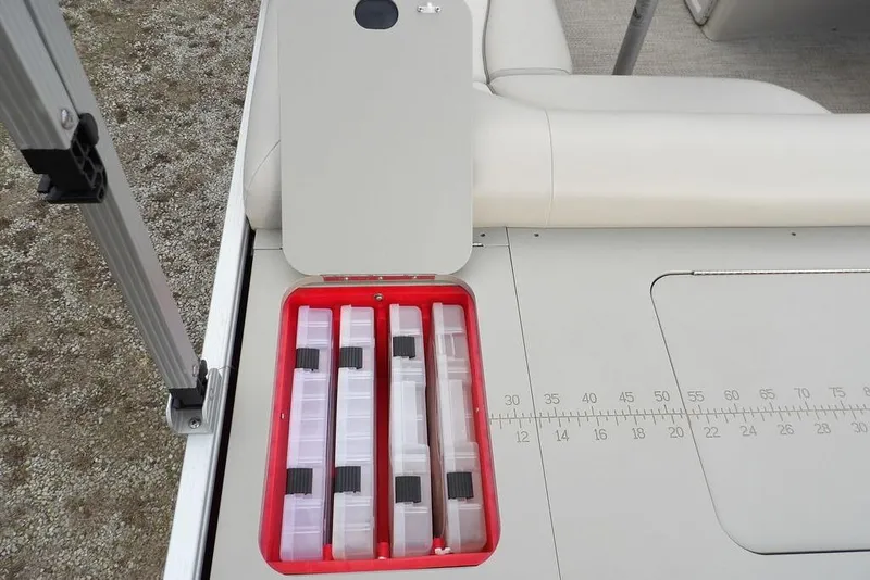 Slide: The Image of 2018 Bennington 23SF boat storage compartment with tackle boxes and measuring ruler. - 57