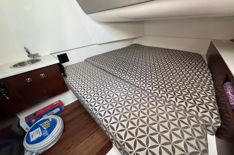 Slide: The Image of 2023 Chaparral 300 OSX cabin interior with patterned bedding and compact sink area. - 23