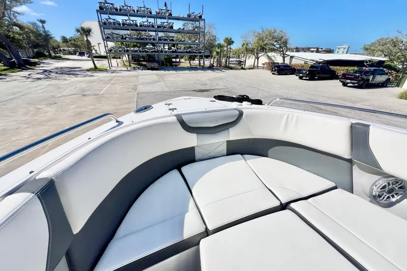 Slide: The Image of 2023 Chaparral 300 OSX boat interior with plush seating, parked near a marina. - 25