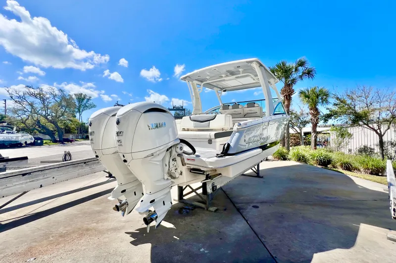 Slide: The Image of 2023 Chaparral 300 OSX boat with dual Yamaha engines, parked outdoors under a clear blue sky. - 4