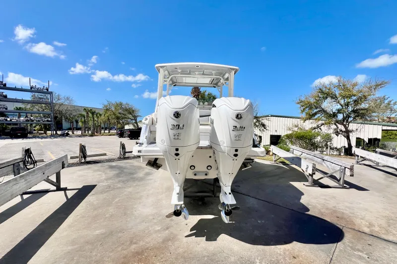 Slide: The Image of 2023 Chaparral 300 OSX boat with dual outboard engines, parked outdoors under a clear blue sky. - 5