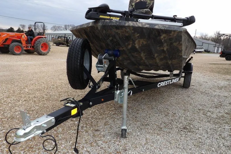 Slide: The Image of 2018 Crestliner 1660 Retriever boat on trailer, camo design, parked on gravel. - 28