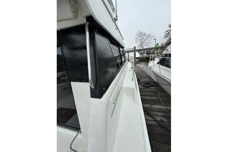 Slide: The Image of 1993 Silverton 34 Convertible yacht docked, side view with visible railing and windows. - 14