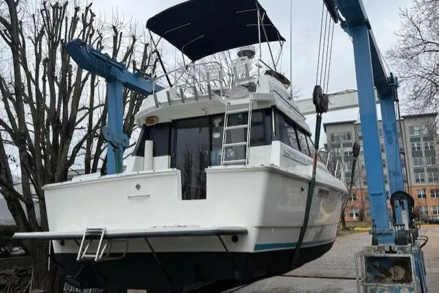 Slide: The Image of 1993 Silverton 34 Convertible boat lifted by crane in a marina setting. - 2