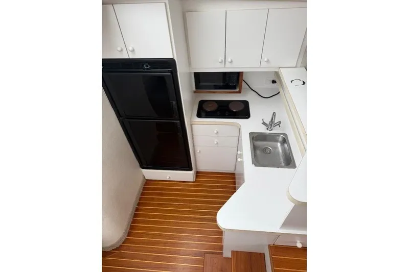 Slide: The Image of 1993 Silverton 34 Convertible yacht kitchen with wood flooring, white cabinets, and appliances. - 38