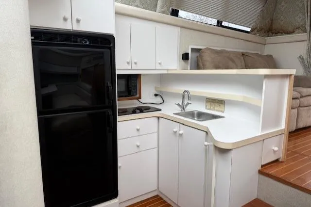 Slide: The Image of 1993 Silverton 34 Convertible yacht kitchen with white cabinets and black appliances. - 39