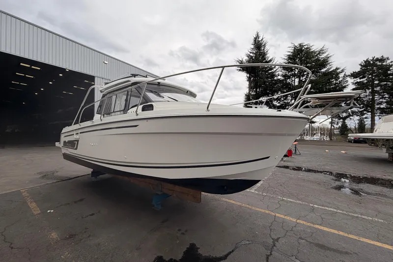 The Image of 2026 Jeanneau NC Weekender 795 Series 2 boat displayed outdoors near a warehouse. - 0