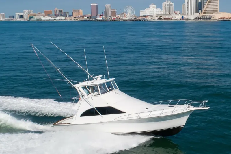 The Image of Ocean Yachts 48 Super Sport 1999 cruising near city skyline on blue ocean waters. - 1