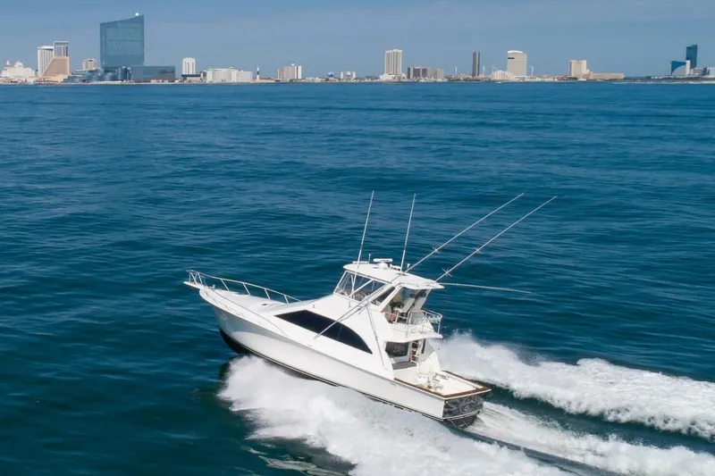 Slide: The Image of 1999 Ocean Yachts 48 Super Sport cruising near city skyline on open water. - 3