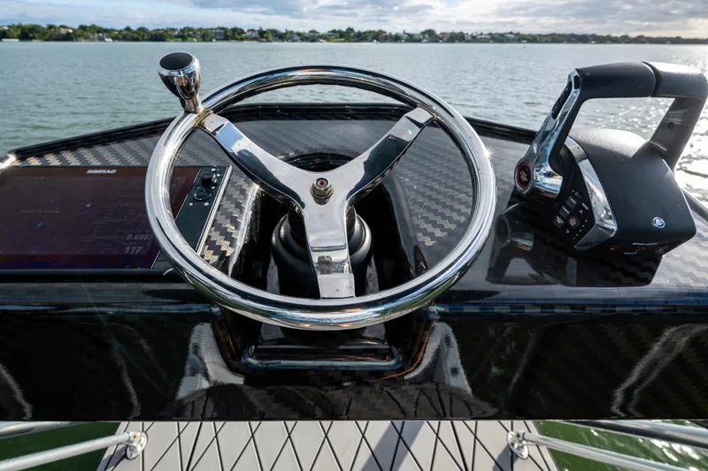 Slide: The Image of 2024 Contender 44 ST boat helm with steering wheel and controls on water. - 24