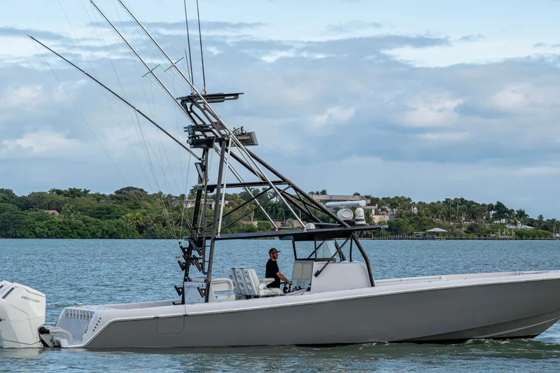 Slide: The Image of 2024 Contender 44 ST boat cruising on a scenic waterway with lush greenery. - 29