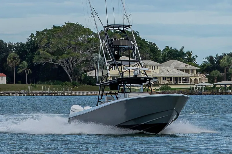 Slide: The Image of 2024 Contender 44 ST boat cruising on water near luxury waterfront homes. - 30