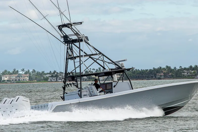 Slide: The Image of 2024 Contender 44 ST boat cruising on water with palm trees in background. - 33