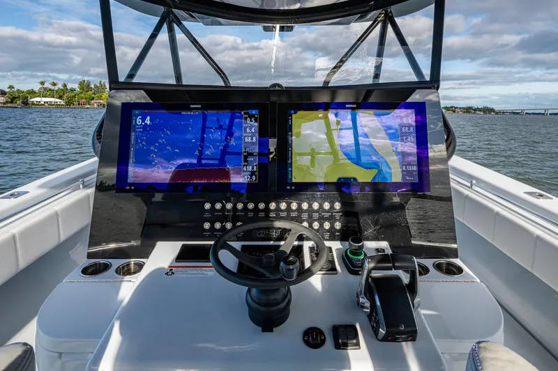 Slide: The Image of 2024 Contender 44 ST boat dashboard with dual navigation screens on open water. - 5