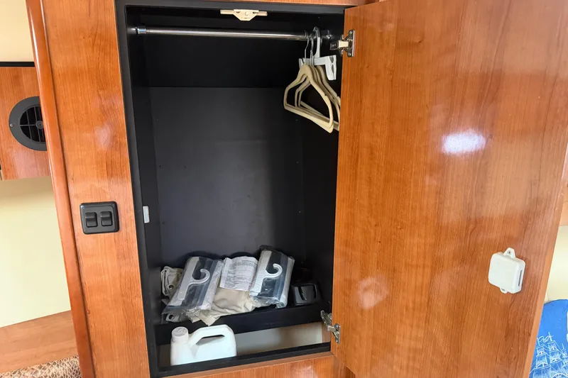 Slide: The Image of Wooden closet interior on 2008 Cruisers Yachts 330 Express, featuring hangers and storage items. - 11