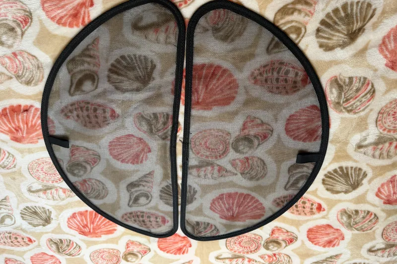 Slide: The Image of Mesh window cover on a 2008 Cruisers Yachts 330 Express, with seashell-patterned background. - 12