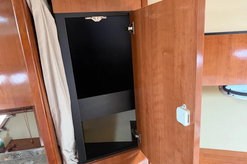 Slide: The Image of Open wooden cabinet inside 2008 Cruisers Yachts 330 Express, showcasing interior storage space. - 13