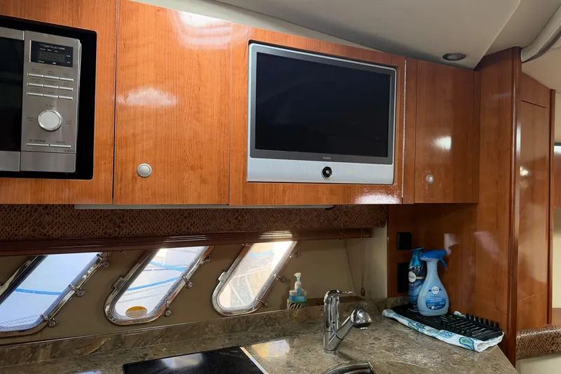Slide: The Image of 2008 Cruisers Yachts 330 Express interior with wood cabinets, TV, and kitchen sink. - 42
