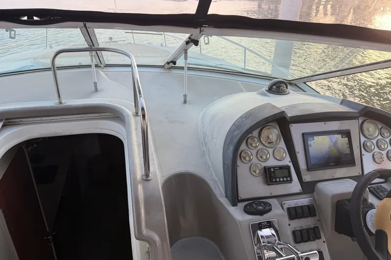 Slide: The Image of 2008 Cruisers Yachts 330 Express helm with navigation controls and gauges, docked by water. - 68