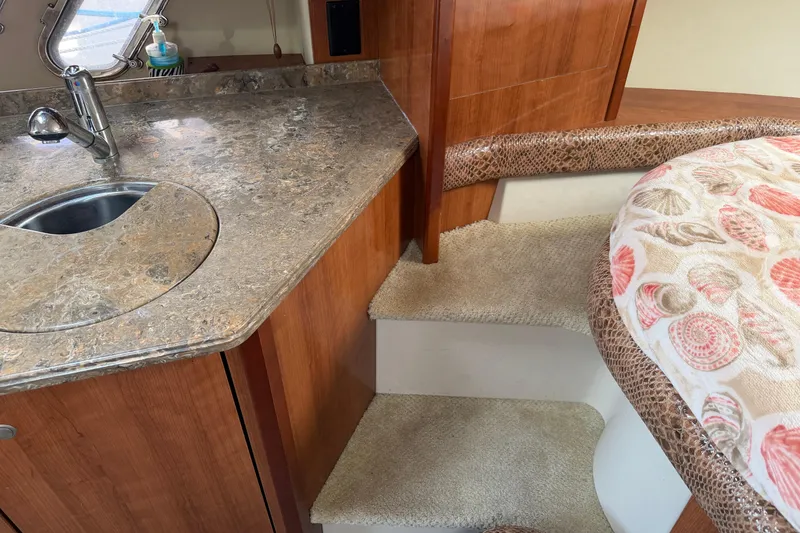 Slide: The Image of 2008 Cruisers Yachts 330 Express interior with sink, countertop, and patterned bedding. - 8