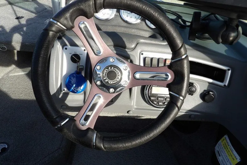 Slide: The Image of Steering wheel of 2025 Lund 1875 Crossover XS boat, featuring modern dashboard controls. - 25