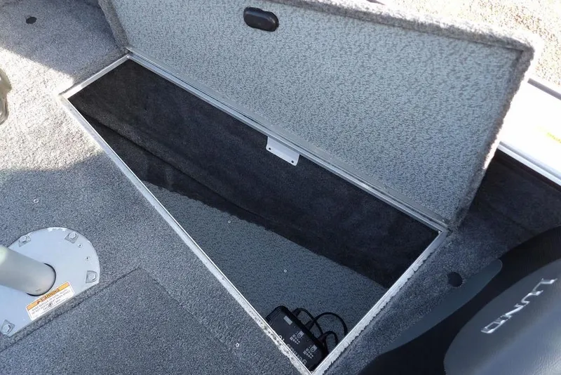 Slide: The Image of Open storage compartment in 2025 Lund 1875 Crossover XS boat, featuring carpeted interior. - 30