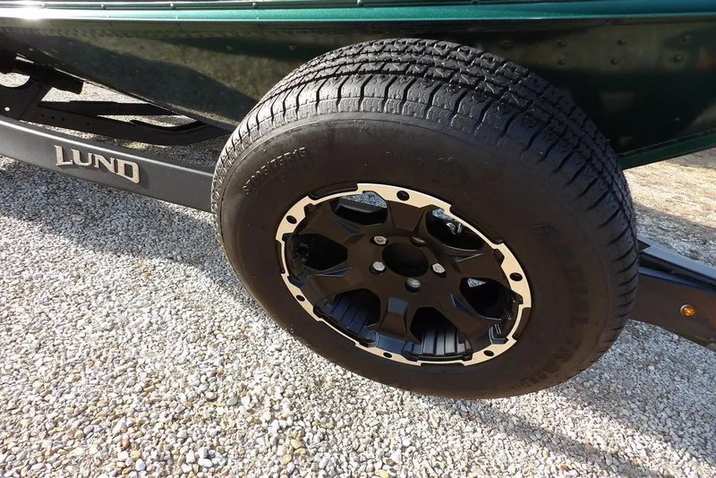 Slide: The Image of 2025 Lund 1875 Crossover XS trailer wheel on gravel surface. - 47