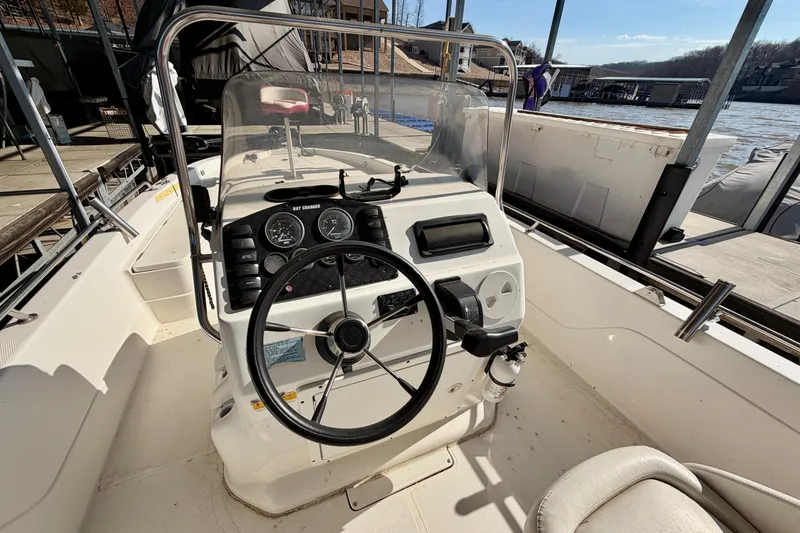 Slide: The Image of 2004 PlayCraft 22 Bay Charger boat cockpit with steering wheel and gauges, docked by the lake. - 10