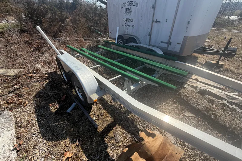 Slide: The Image of Trailer for 2004 PlayCraft 22 Bay Charger boat, parked on gravel near a construction trailer. - 29