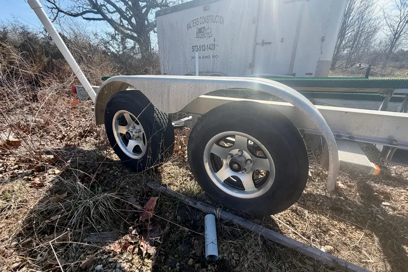 Slide: The Image of 2004 PlayCraft 22 Bay Charger trailer with dual wheels in a grassy area. - 30