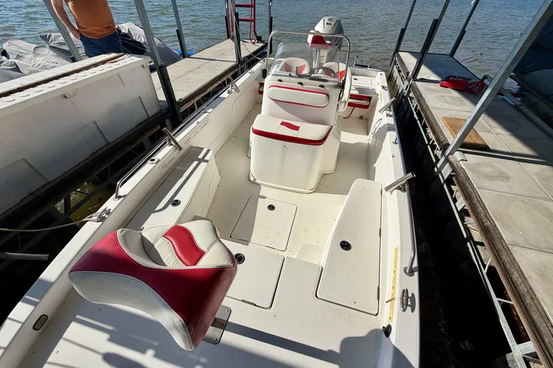 Slide: The Image of 2004 PlayCraft 22 Bay Charger boat interior with red and white seating, docked by the water. - 6