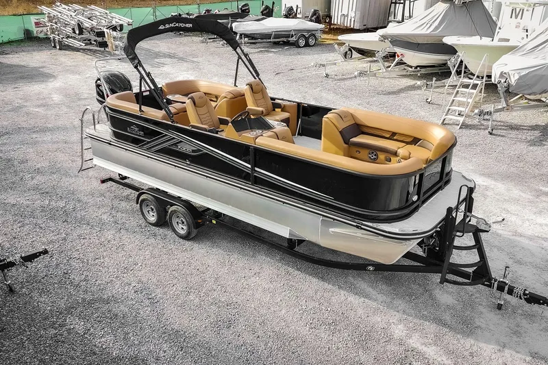 The Image of 2025 SunCatcher Fusion 324RC pontoon boat on trailer, parked in a marina. - 1