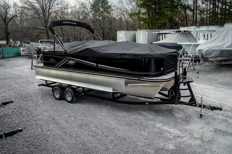 Slide: The Image of 2025 SunCatcher Fusion 324RC pontoon boat on trailer, covered and parked outdoors. - 4