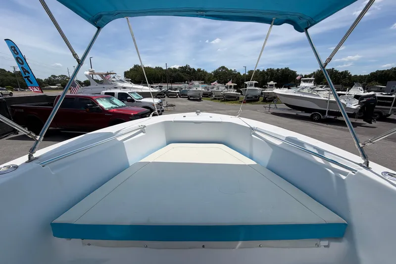 Slide: The Image of 2005 Angler 204CC boat interior with blue canopy, parked in a marina. - 31