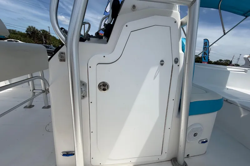 Slide: The Image of 2005 Angler 204CC boat console with storage compartment and seating, under a clear blue sky. - 44