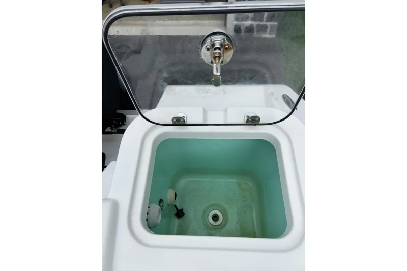 Slide: The Image of Livewell on 2023 NauticStar 24 Legacy boat, featuring a transparent lid and faucet. - 14