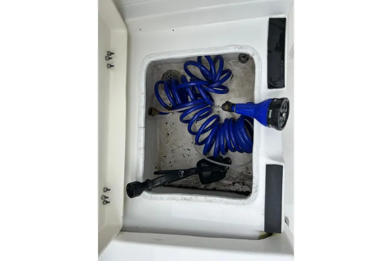 Slide: The Image of Storage compartment with blue coiled hose on 2023 NauticStar 24 Legacy boat. - 17